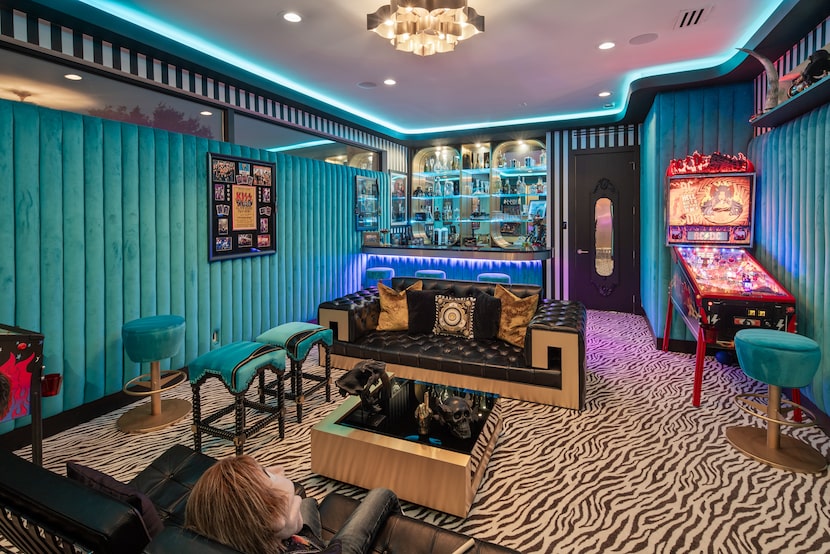 Turquoise channel-tufted walls and zebra-print carpet give this lounge a distinct look. 