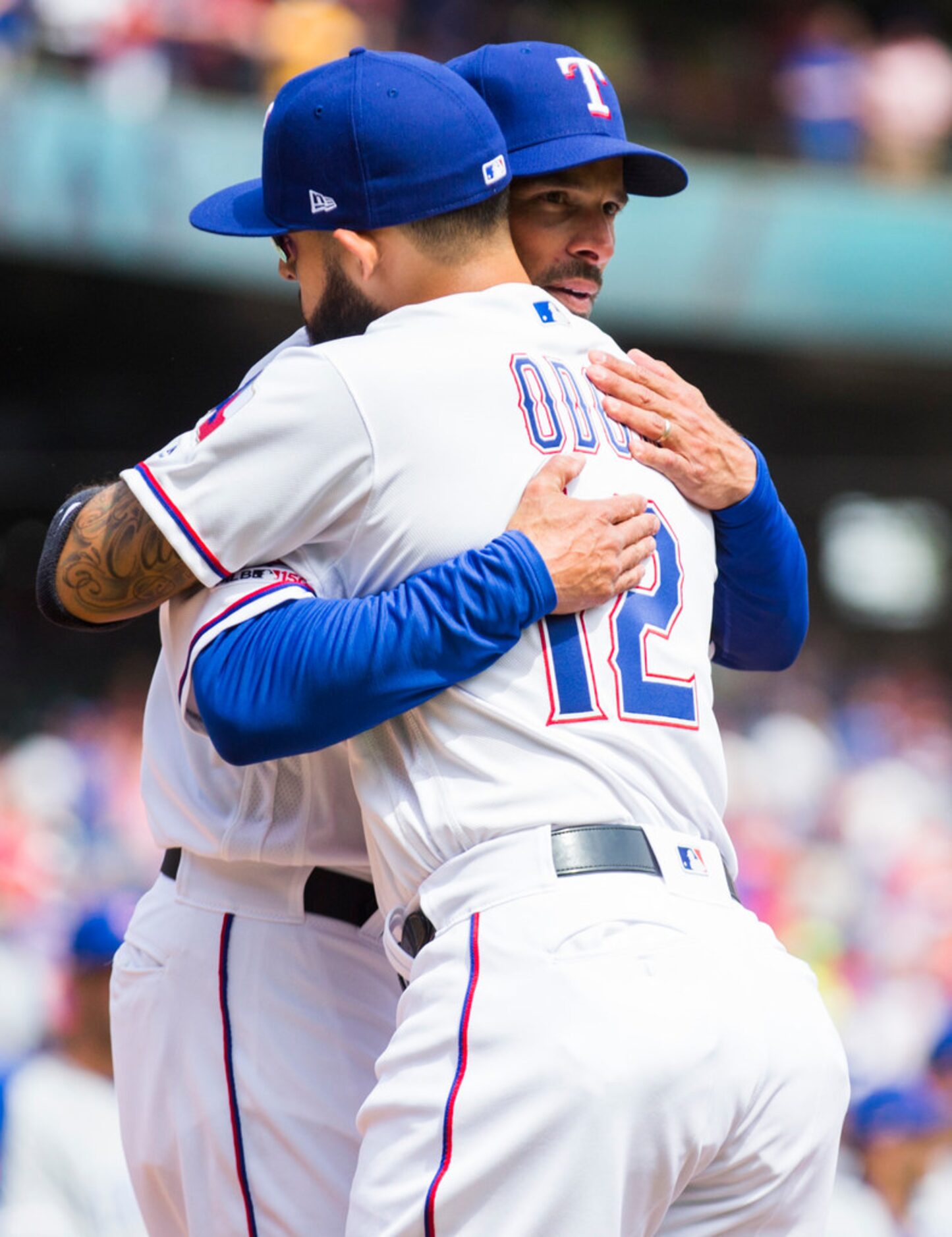 Texas Rangers manager Chris Woodward (8) hugs second baseman Rougned Odor (12) before an...