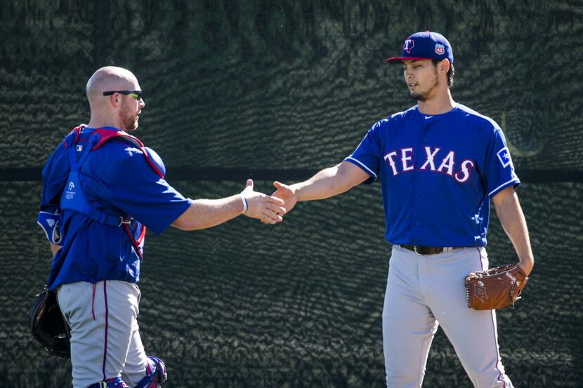 Texas Rangers pitcher Yu Darvish shakes hands with catcher Chris Gimenez after throwing from...