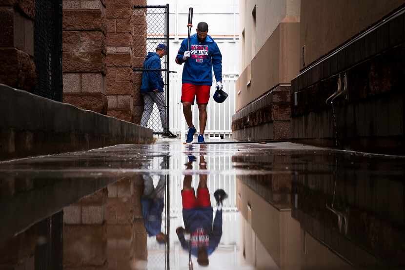 Texas Rangers outfielder Nomar Mazara walks through puddles as he heads from the batting...