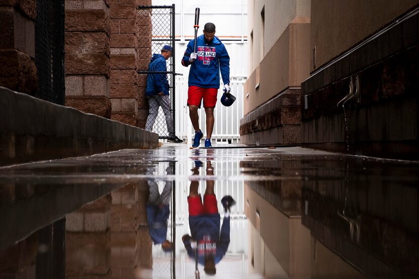 Texas Rangers outfielder Nomar Mazara walks through puddles as he heads from the batting...