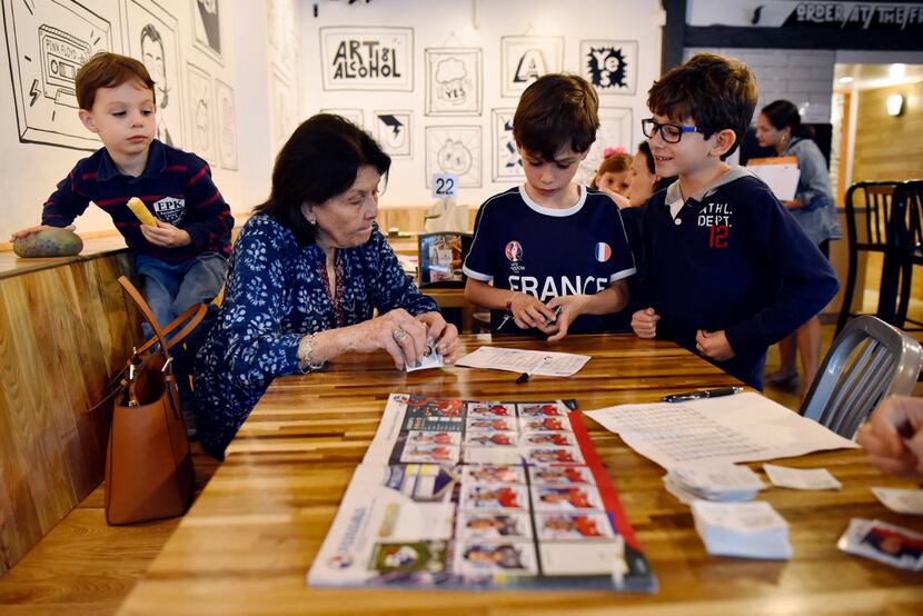 Carmen de Paoli works with a group of kids organizing Panini stickers, including Sebastian...