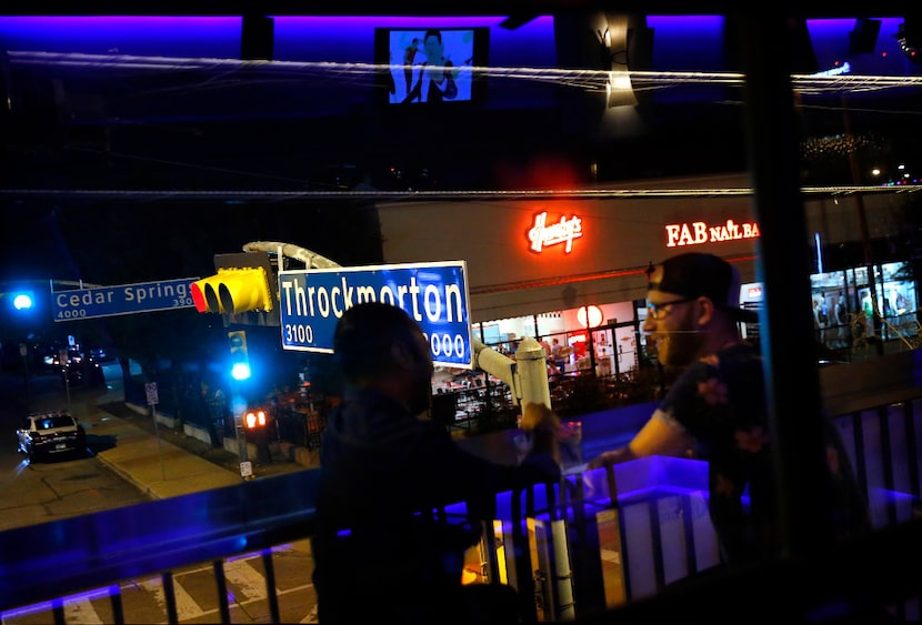 JR's Bar and Grill patrons visit on the upper-level deck near the Throckmorton Street sign...