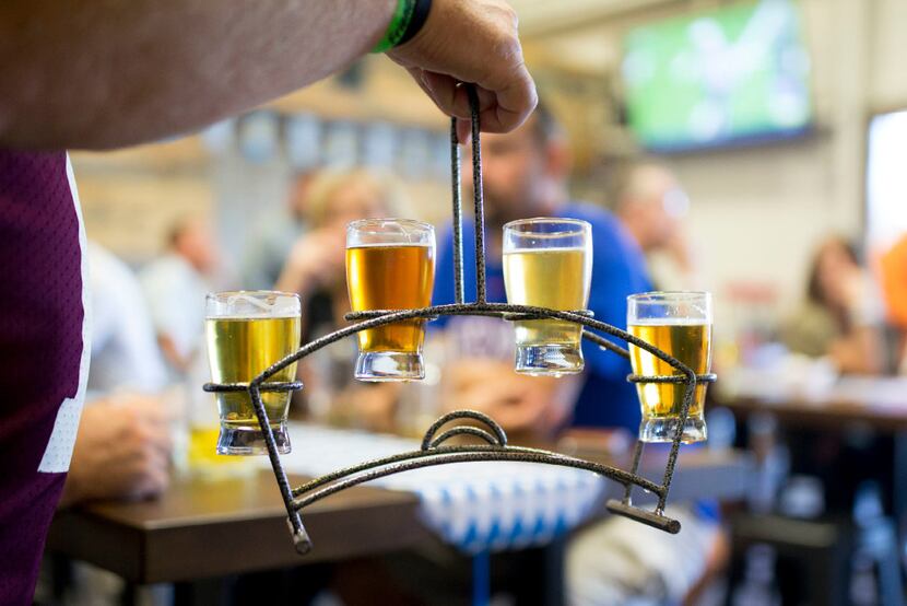 A bar goer carries a flight of beer samplers at Whistle Post Brewing Co. in Pilot Point, Texas.