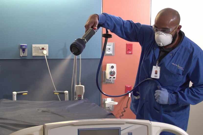 A health care worker sprays down a hospital bed with the continuously active disinfectant,...
