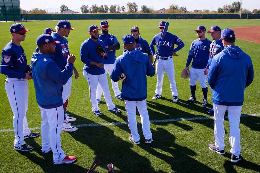 Texas Rangers position players huddle around third base coach Tony Beasley before beginning...