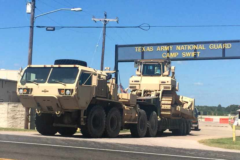 Heavy equipment rolls out of Texas Army National Guard Camp Swift outside of Bastrop on July...