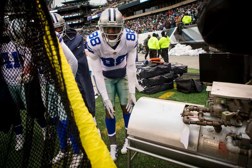 Dallas Cowboys wide receiver Dez Bryant warms his hands in front of a sideline heater...