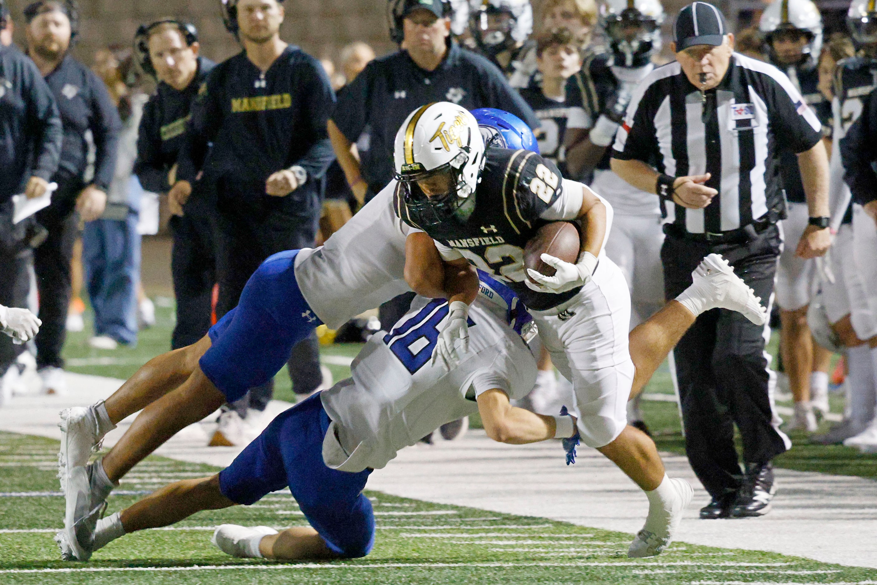 Mansfield's Jayden Vasquez (22) is tackled by Weatherford's Micah Moore (1), left, and...