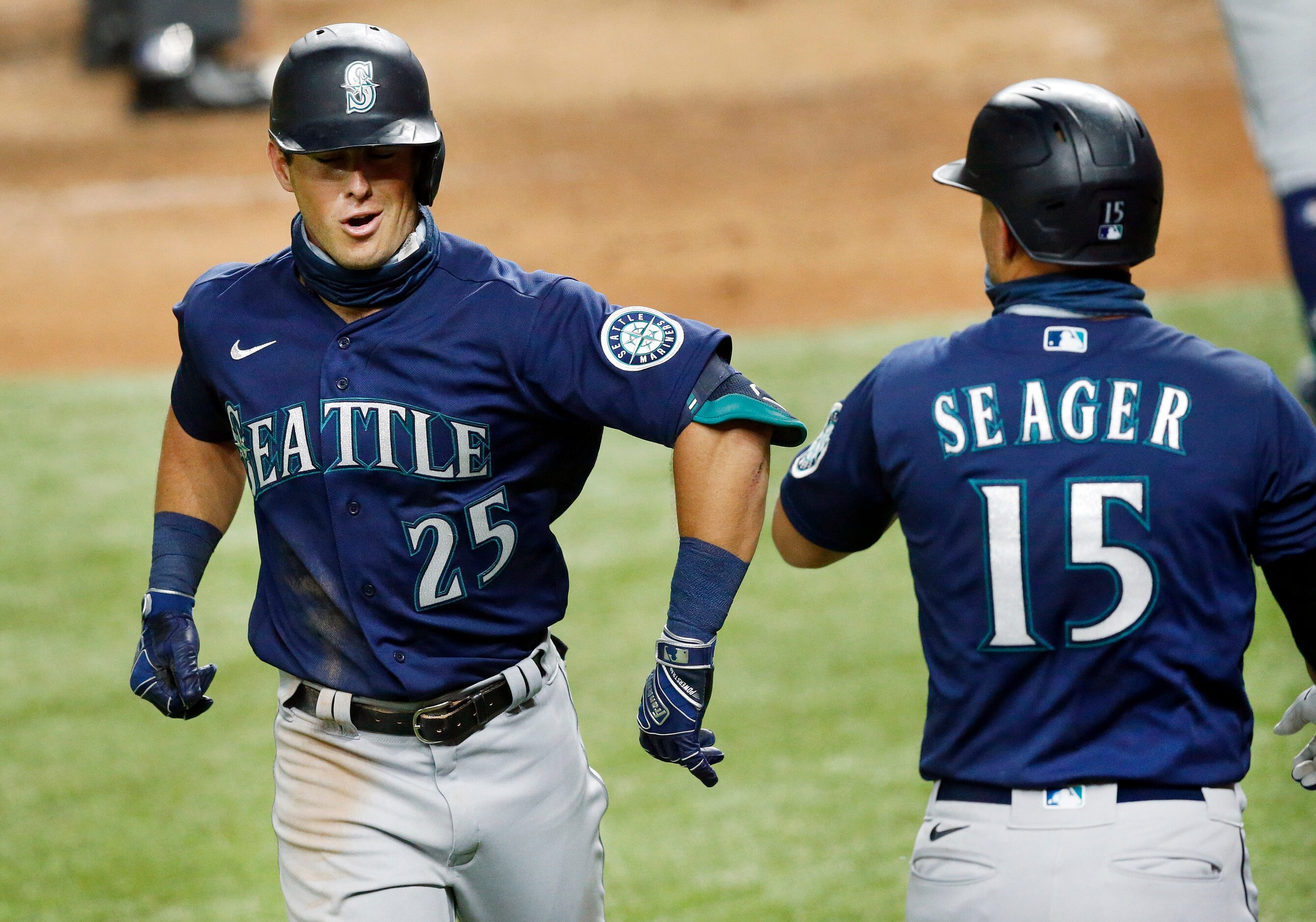 Seattle Mariners Dylan Moore (25) receives and elbow bump from teammate Kyle Seager (15) ...