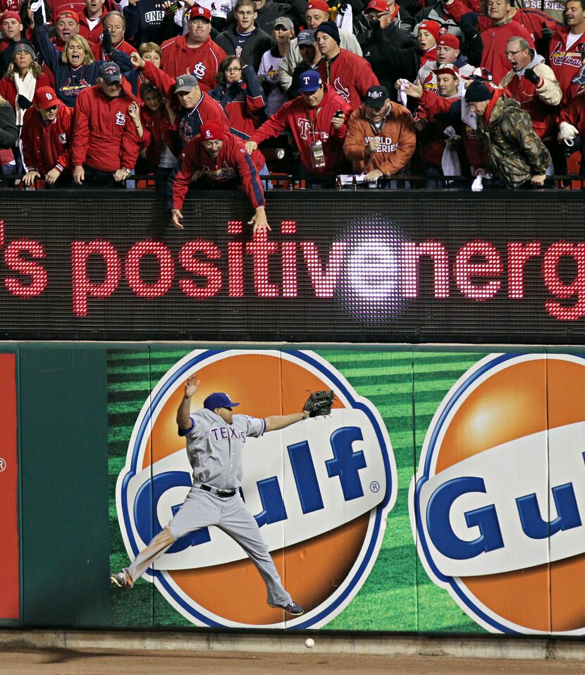 St. Louis Cardinals fans reach as Texas Rangers right fielder Nelson Cruz can't come up with...