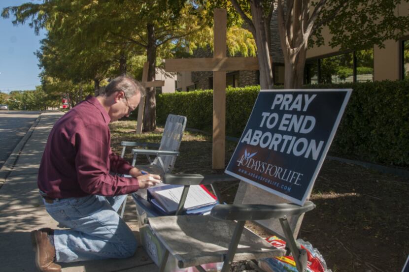 Lee Valerius adds his name to the list of people holding a prayer vigil outside the...