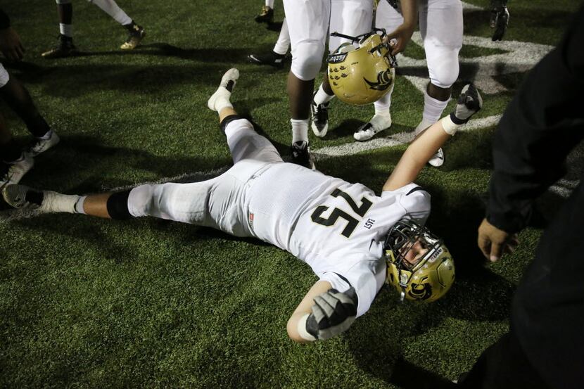 Plano East offensive lineman Casey Verhulst (75) celebrates on the ground following a high...