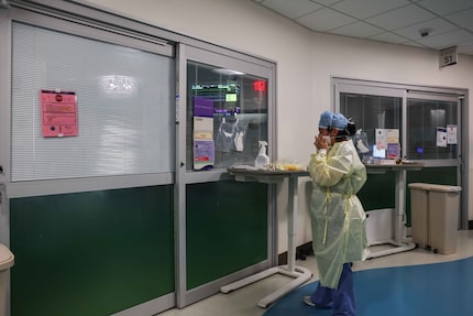 Nurse Christina Walker makes sure a mask properly protects her face before entering the room...