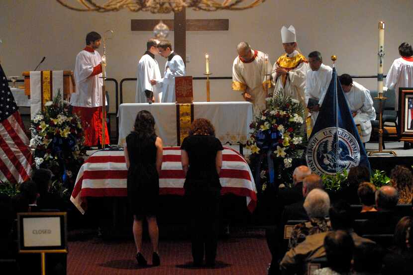 Two women bow before the casket of slain Immigration and Customs Enforcement special agent...