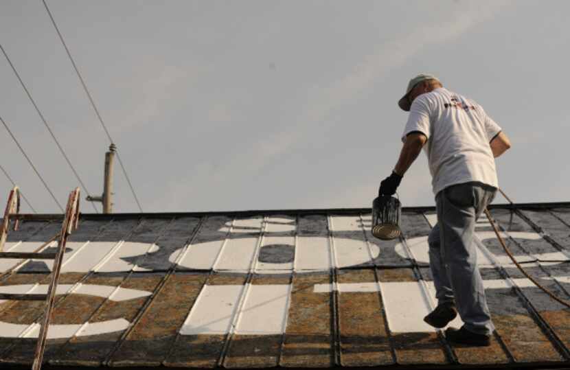 In this March 29, 2012, photo, Don Parris repaints "See Rock City" on the top of an old barn...