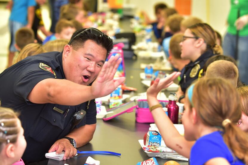 Hickory Creek police officer Mike Miller high fives a Corinth Elementary student during...