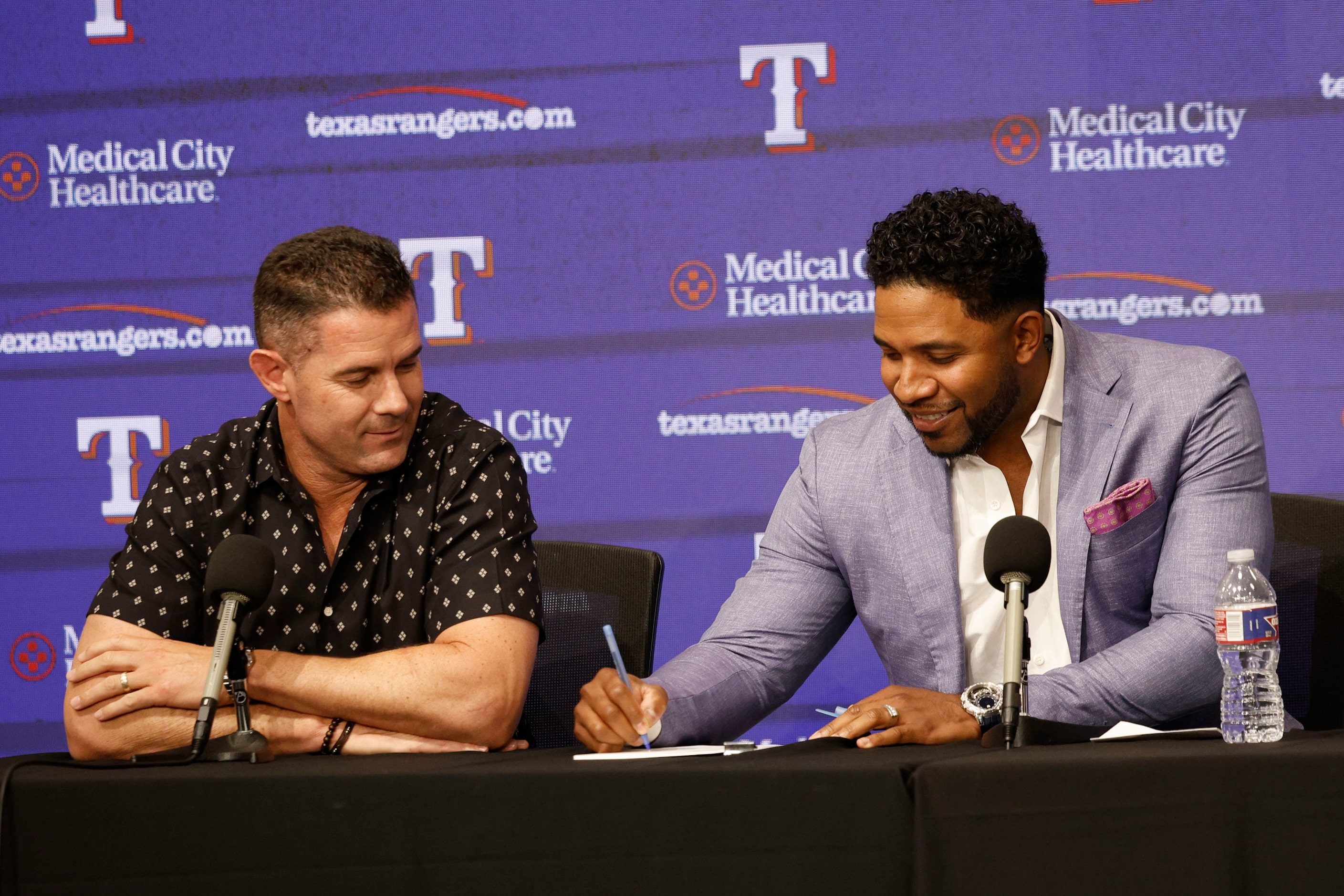 Texas Rangers' Elvis Andrus, right, signs a one-day contract as Michael Young, left,...