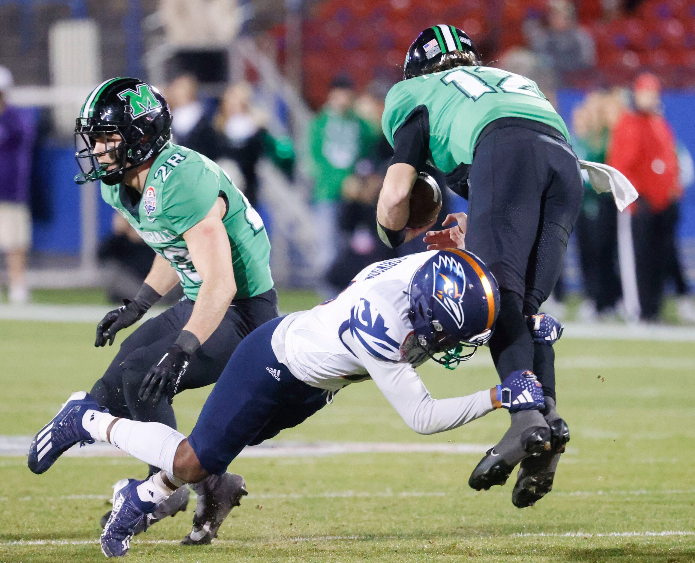 UTSA defensive back Ken Robinson (center) tackles Marshall quarterback Cole Pennington...