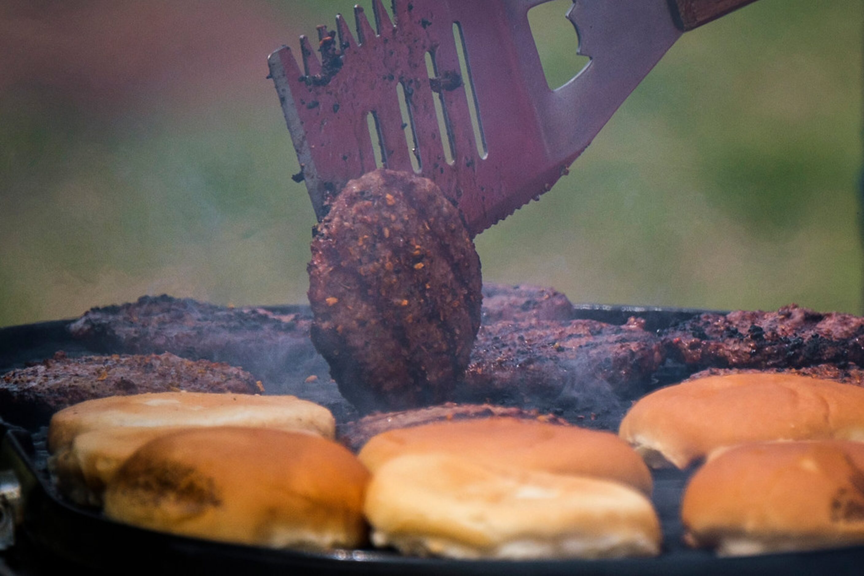 A fan turns a burger on the grill while tailgating before the Texas Rangers opening day game...