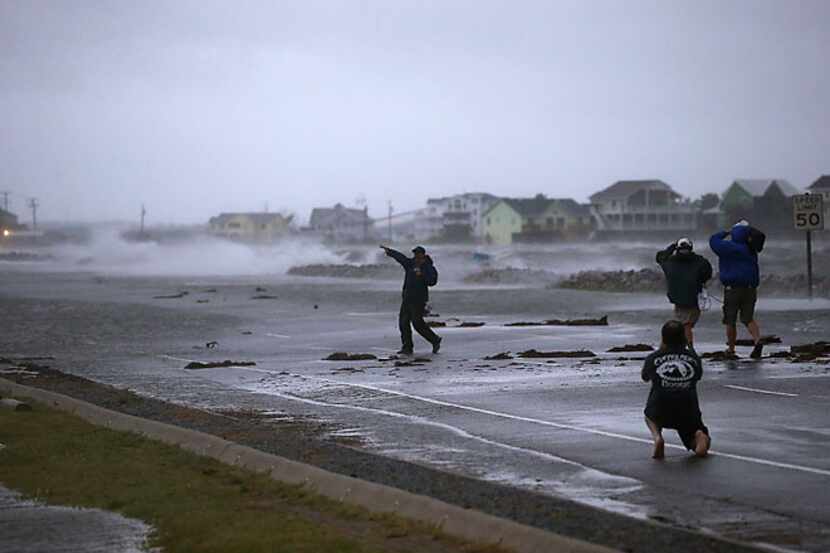 A TV news crew shoots a report from the flooded Highway 64 Friday in Nags Head, N.C....
