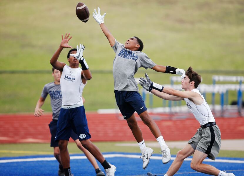 TXHSFB Fort Worth All Saints freshman wide receiver Jay Williams, center, reaches for a pass...