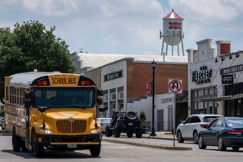 A Frisco ISD school bus passes along Main Street under the city's iconic water tower. The...