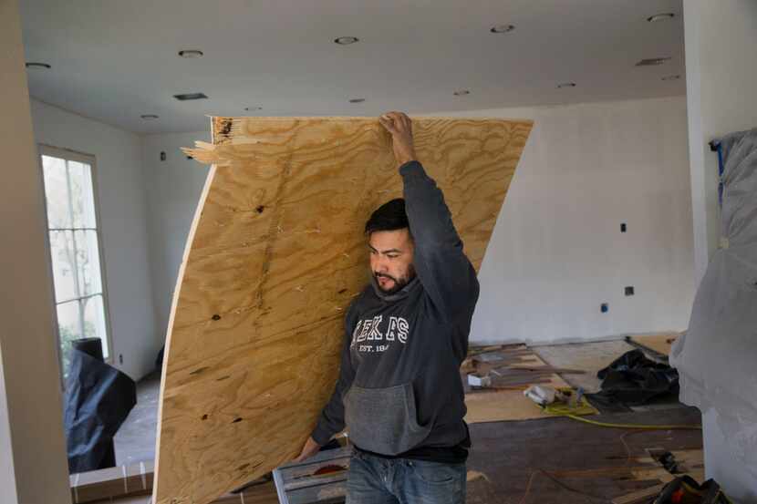 A contractor working for Marvelous Home Makeovers carries plywood at a home being remodeled...