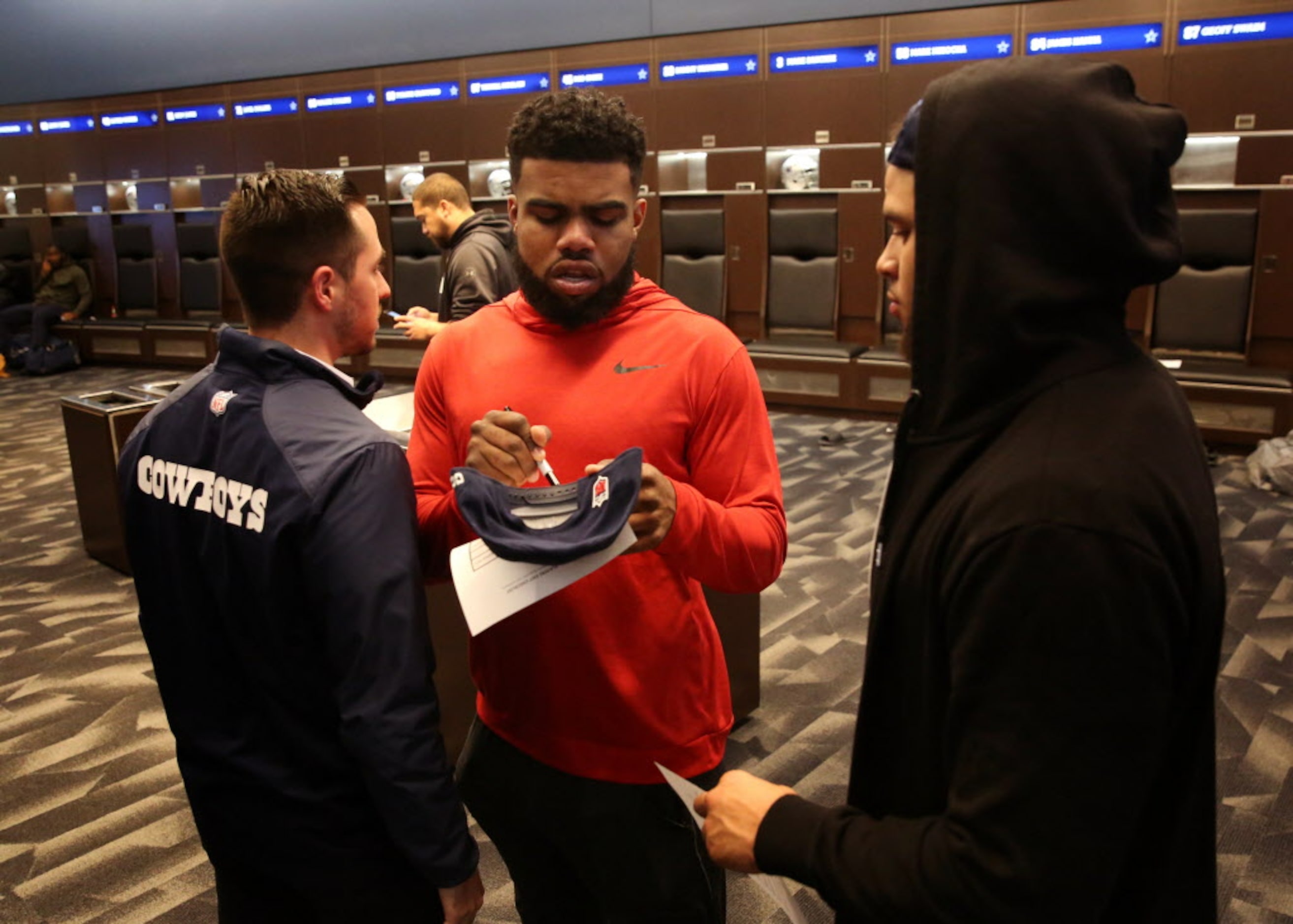 Dallas Cowboys running back Ezekiel Elliott signs a hat for fullback Keith Smith during...