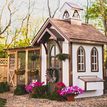 Chapel-style chicken coop with flowers around it and trees