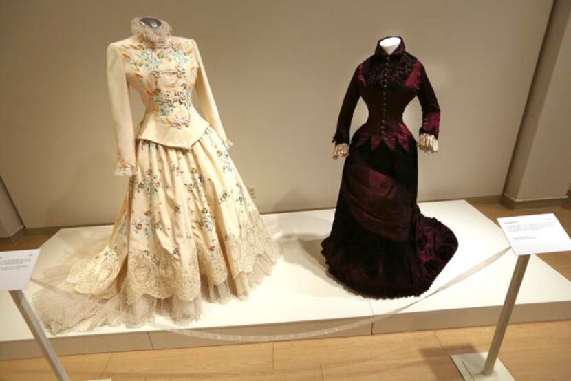 
A wedding dress from a 1993 wedding is displayed with a dress made in 1878 in “American...