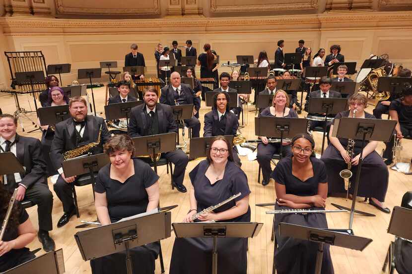 A diverse group of musicians sits onstage with their instruments at Carnegie Hall