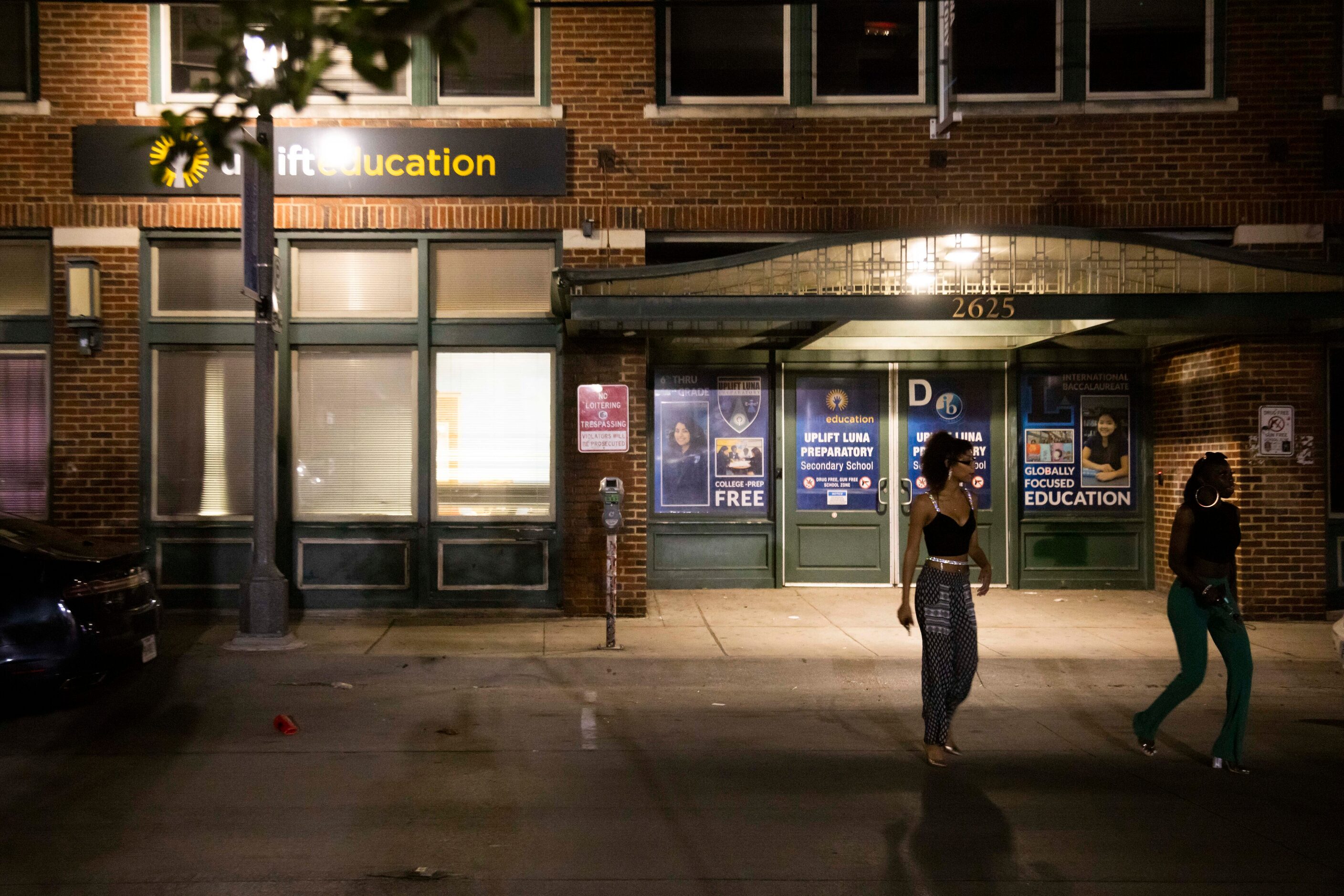 People cross the street in front of Uplift Luna Preparatory in the Deep Ellum district of...