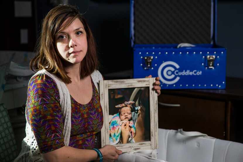 Chelsea Schwartz holds a photo of her stillborn daughter, Talia Joy, next to a bassinet and...