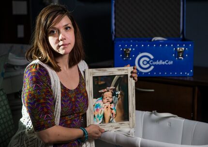 Chelsea Schwartz holds a photo of her stillborn daughter, Talia Joy, next to a bassinet and...