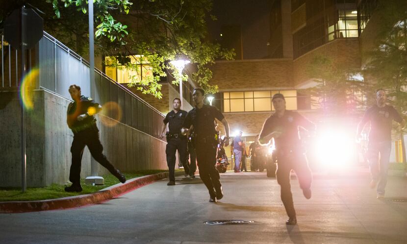 Police officers at Texas Health Presbyterian Dallas race to their cars to join other...
