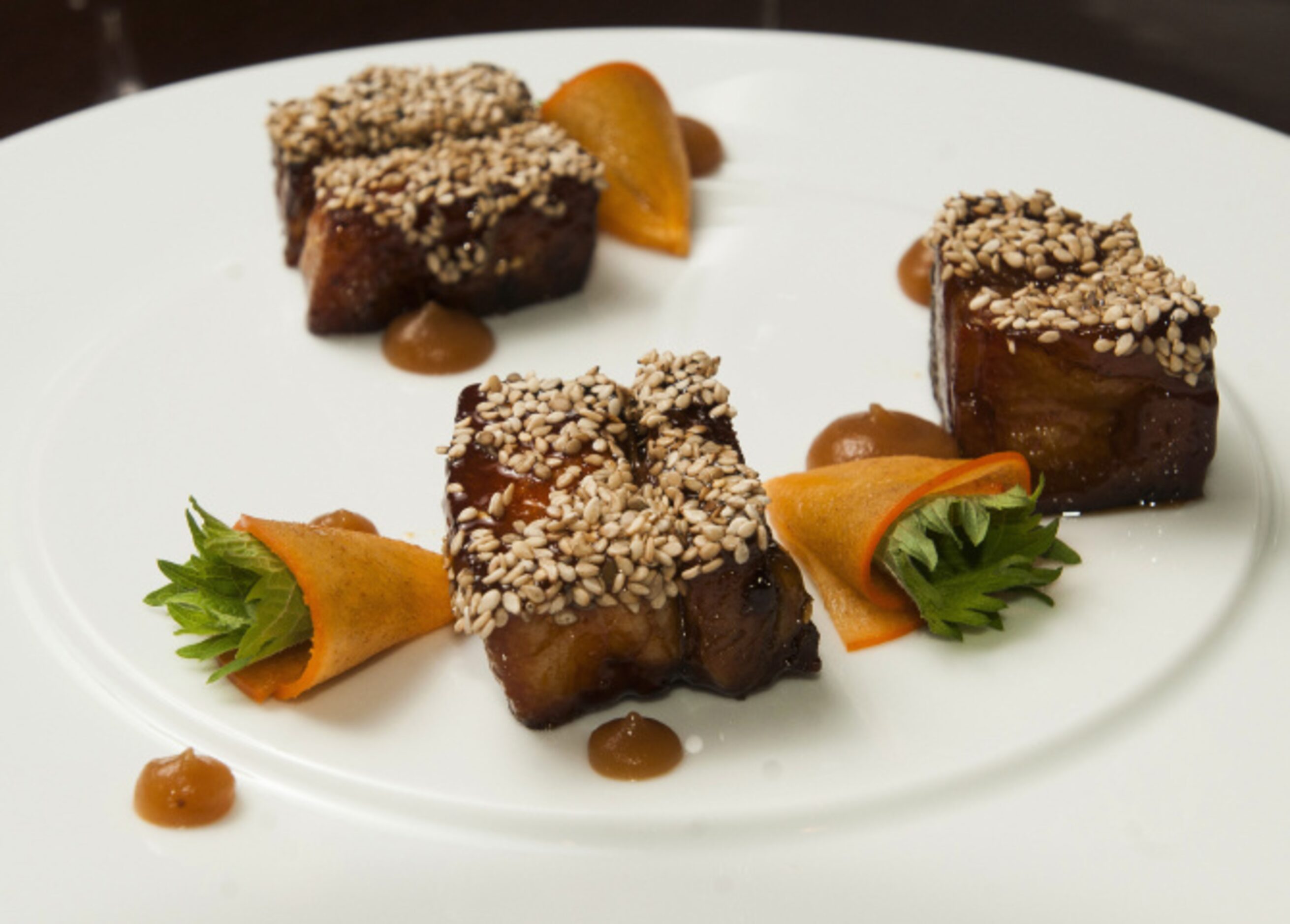 Bourbon-glaze, benne-seed-crusted pork belly with persimmon, caramelized rutabaga puree and...