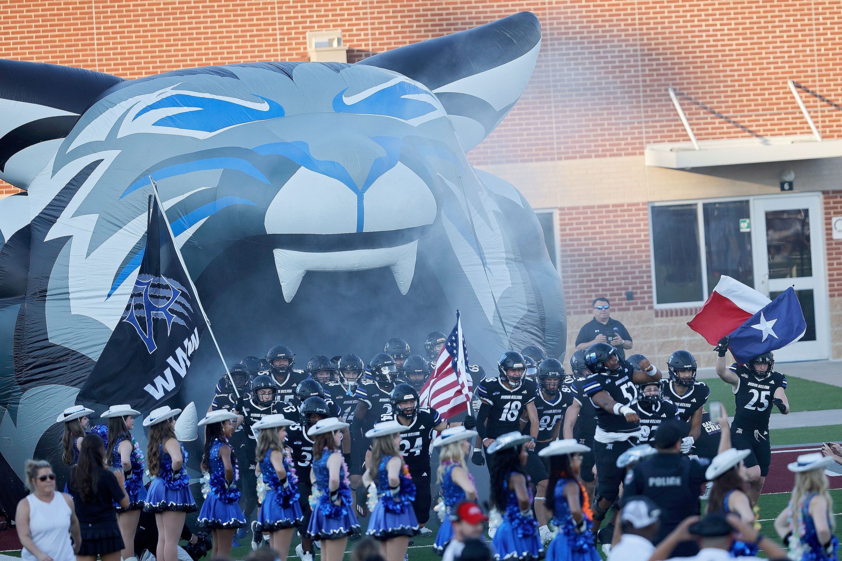 Byron Nelson's players run to the field before a high school football game against...