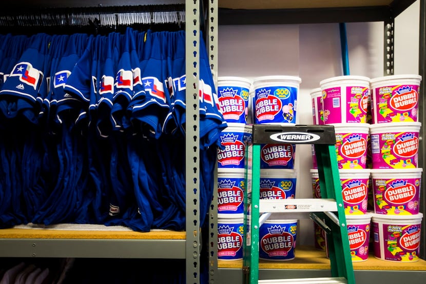 Jerseys and tubs of bubble gum fill shelves in the equipment room at Texas Rangers newly...