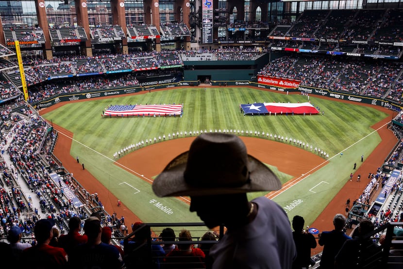 Hector Camarena of Fort Worth is silhouetted as fans stands before the Texas Rangers’ home...
