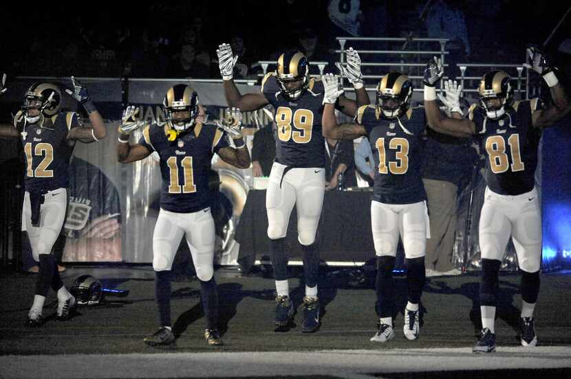 Members of the St. Louis Rams raise their arms in awareness of the events in Ferguson, Mo., ...
