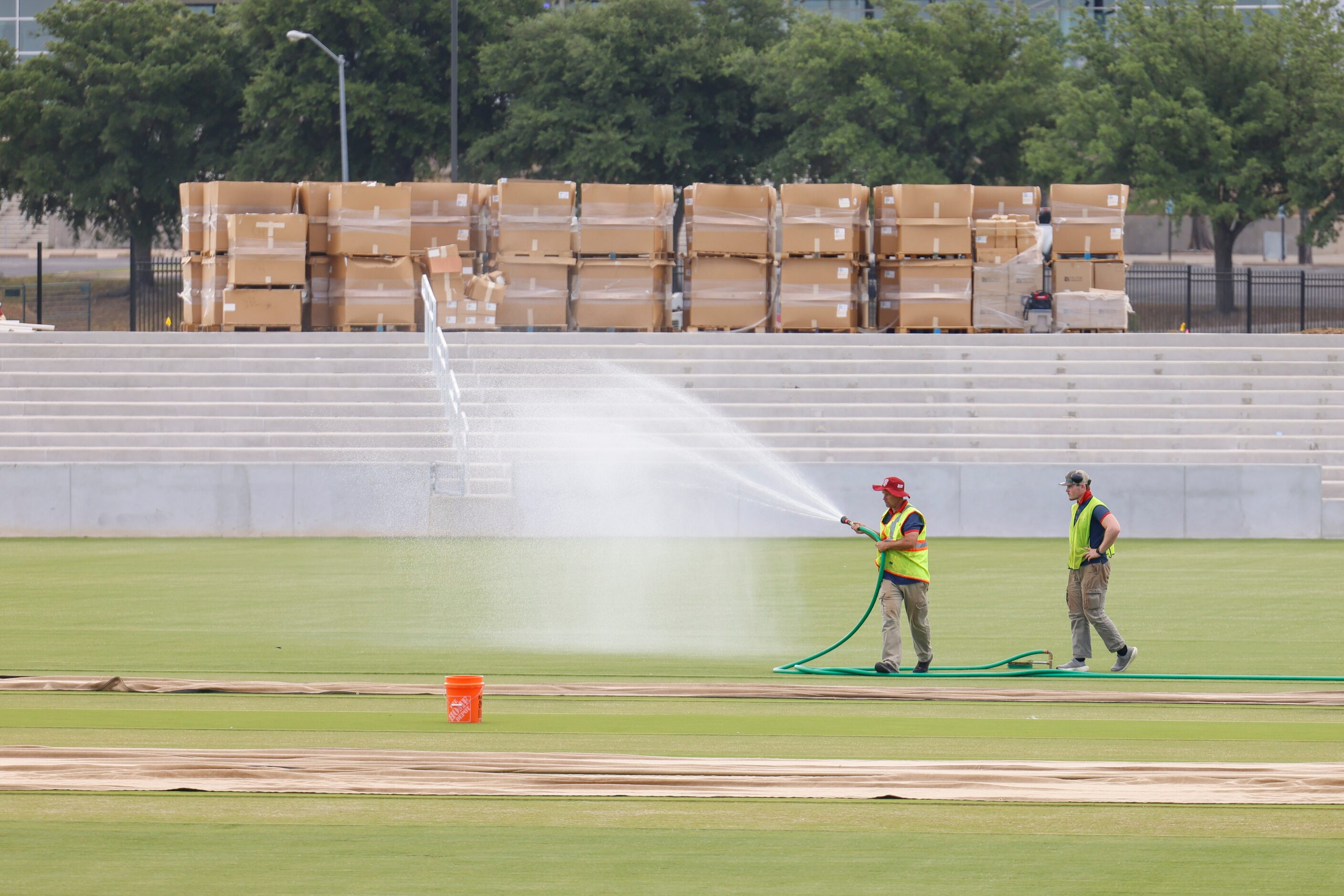 Groundsman Trent Kelly (front) waters the ground as he curates the cricket pitch on...