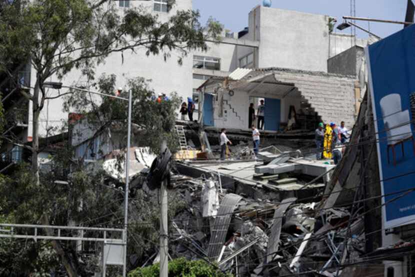 
				Trabajadores de rescate y voluntarios buscan en un edificio derrumbado en el centro de...