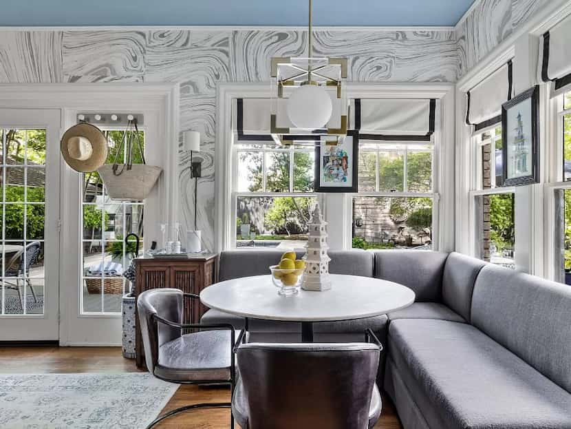 Breakfast room with statement white-and-gray wallpaper, a gray bench, table and chairs and...