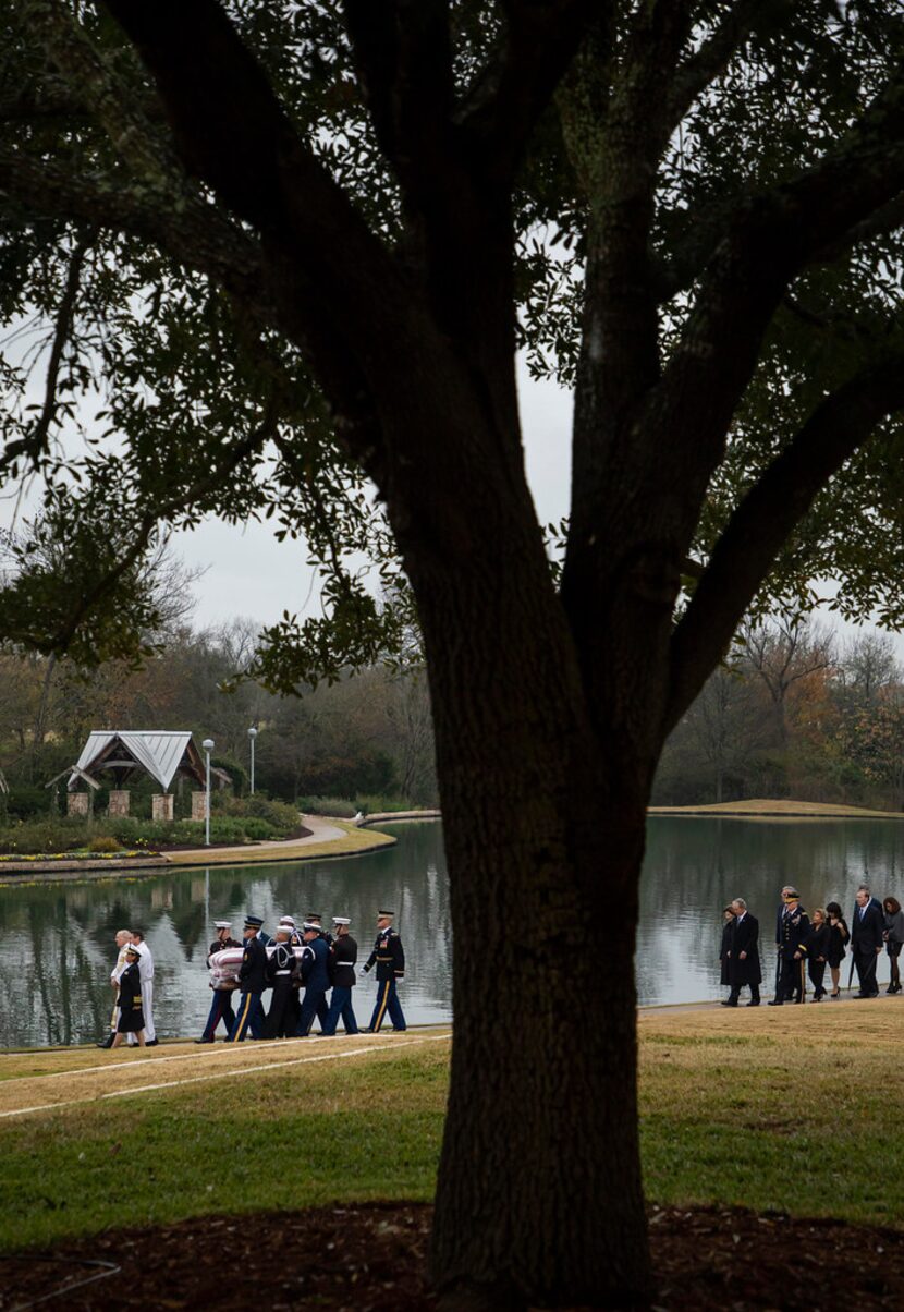 The flag-draped casket of President George H.W. Bush is followed by his family as he is...