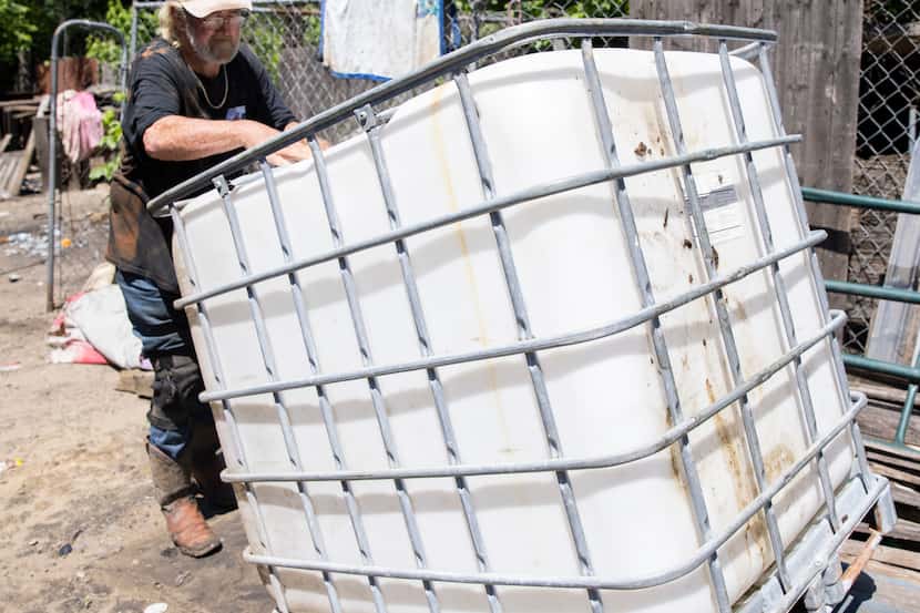 Richard Shivers flips over the water container tank he uses to transport water to the lot...