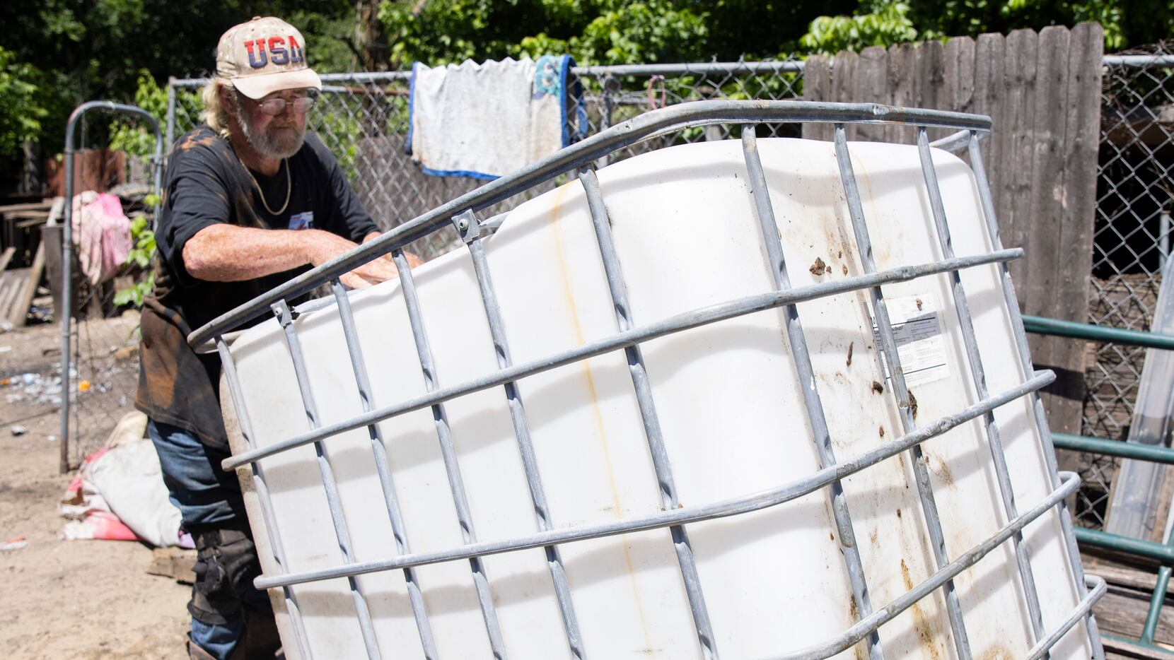Richard Shivers flips over the water container tank he uses to transport water to the lot...
