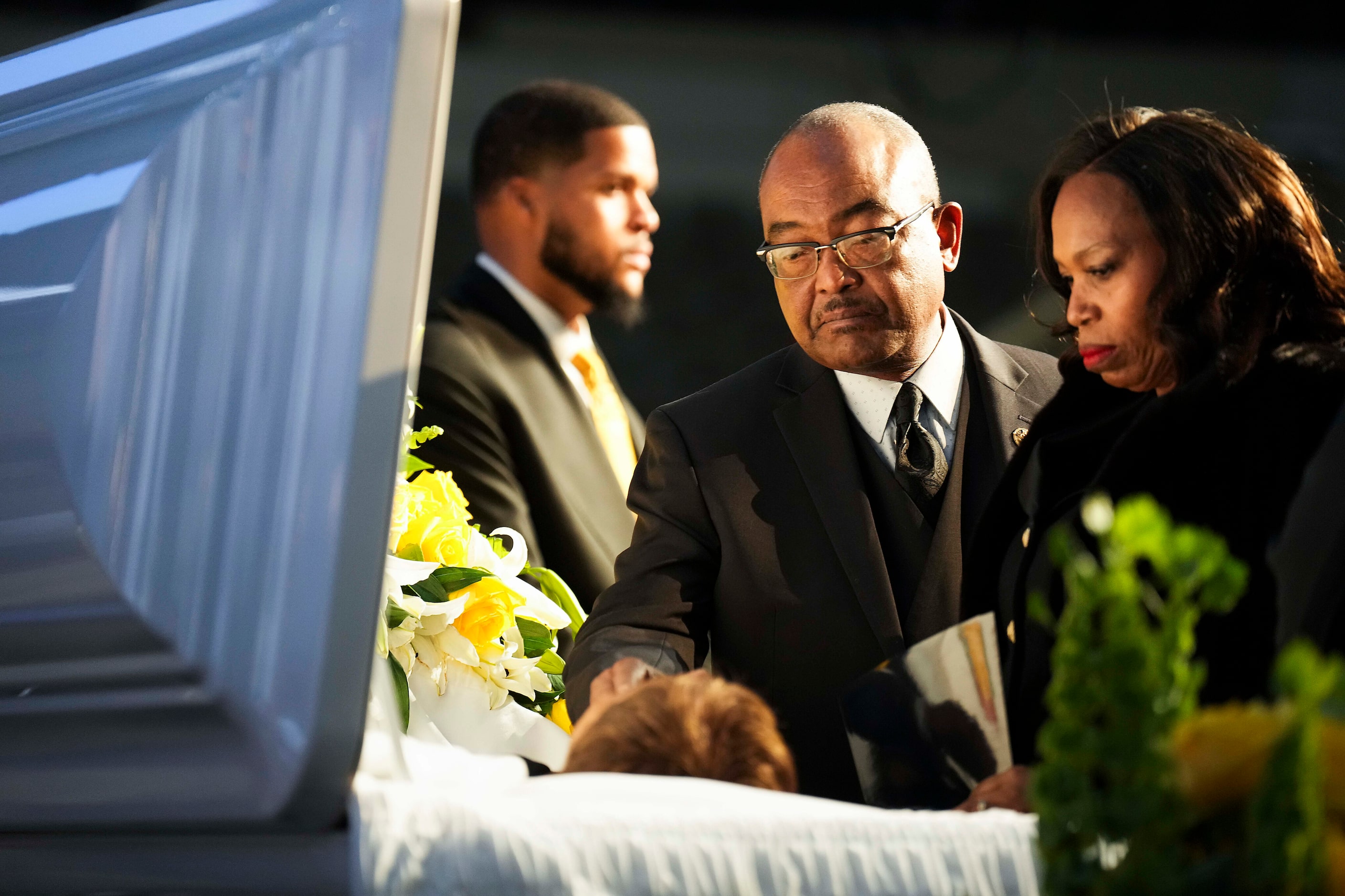 Kirk Johnson reaches into his mother’s casket  during funeral services for former U.S. Rep....