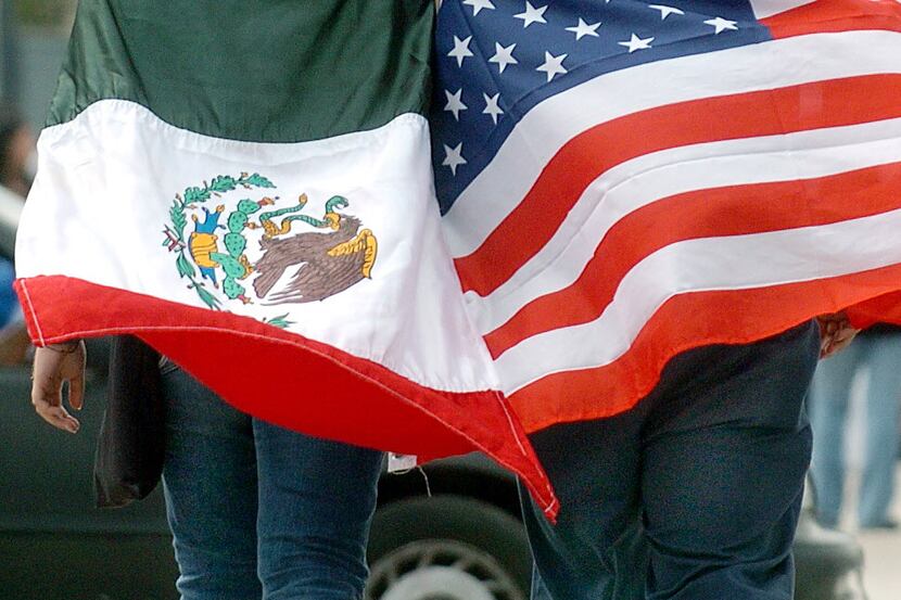 Demonstrators wear the flags of Mexico and the United States as they walk across Mission...