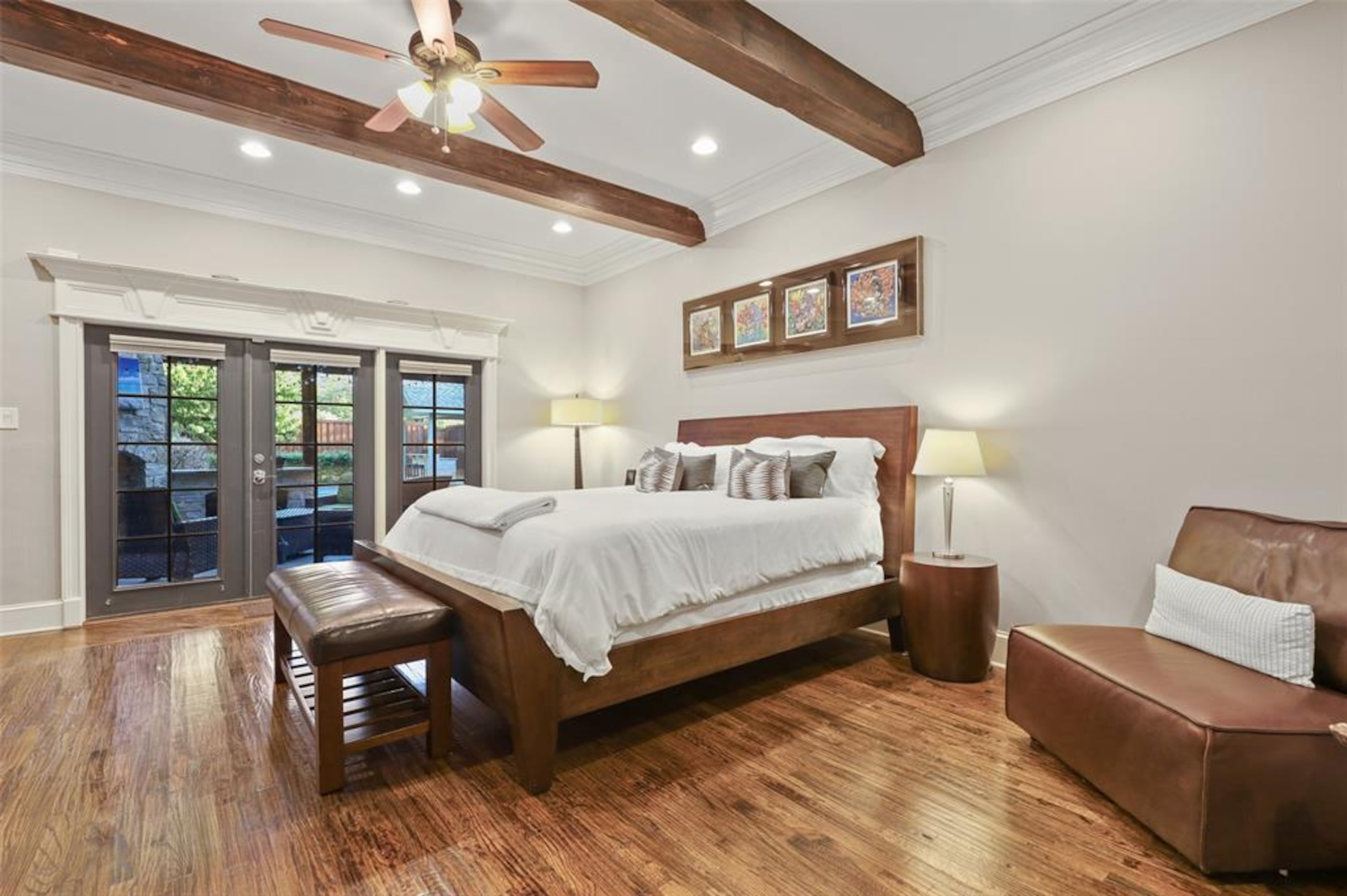 Primary bedroom with wooden beams across the ceiling and white walls.